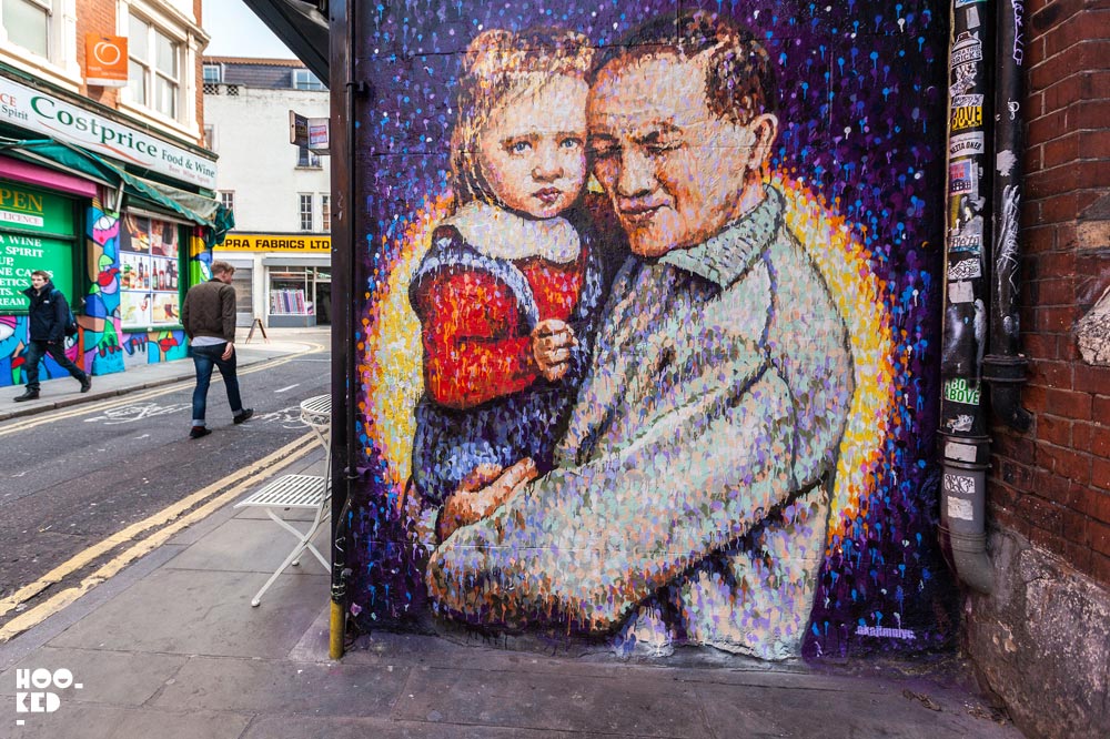 Jimmy C aka James Cochran - Brick Lane Street Art on Fashion Street, London featuring a painting of a father and their child in his arms