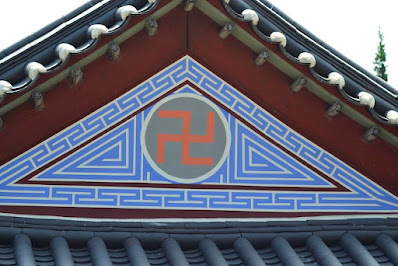 Orange swastika in a circle surrounded by blue geometric patterns. Bongeunsa temple, South Korea.