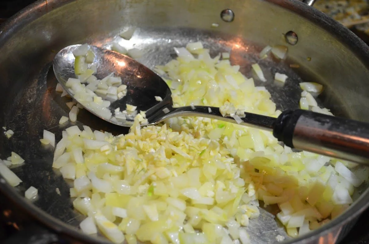 Saute onions with garlic in a pan for Mexican Rice.