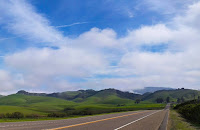 Image of a road stretching out of view and getting lost in a rolling, grassy hillside