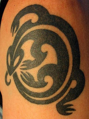 Big circle tribal lizard tattoo design on upper arm.