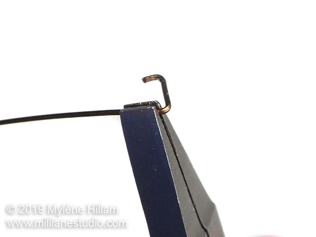 Bending the wire in the flat nose pliers at a 60° angle.