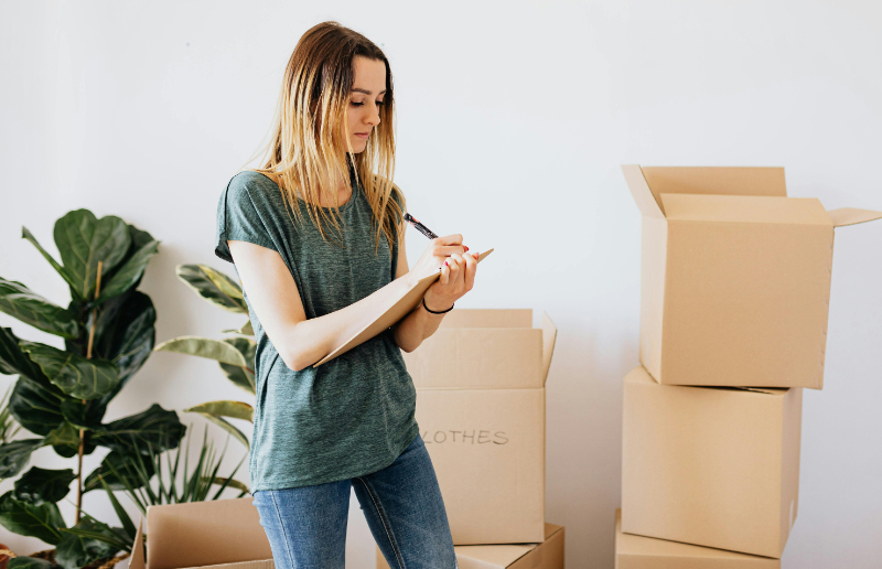 A woman writing down notes while packing her belongings