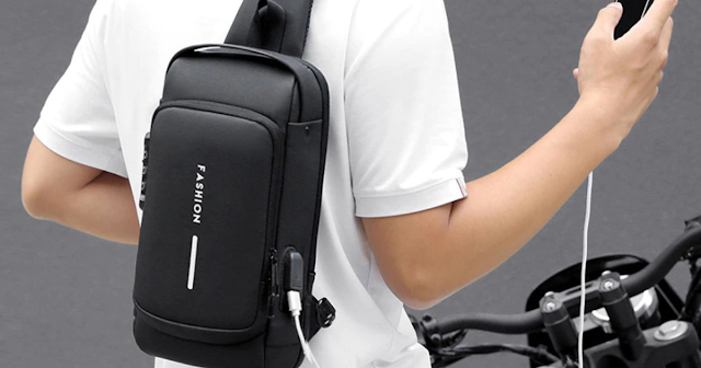 Man carrying a multifunction antitheft crossbody bag while charging his smartphone