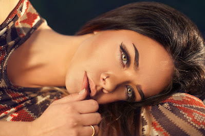 Mujer posando de lado, con la cabeza reposando sobre el brazo y ojos maquillados