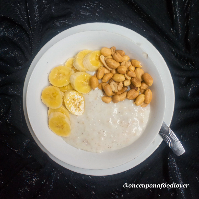 A plate of oatmeal porridge with sliced banana and peanuts