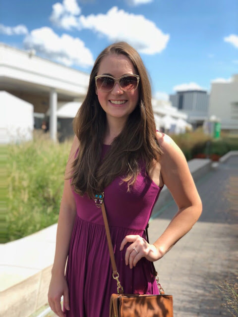 Model is wearing a fuchsia-purple maxi-dress with neutral-colored sandals and accessories.