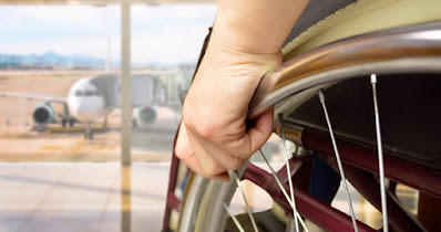 Side view of person in wheelchair in an airport looking out at an airplane photo