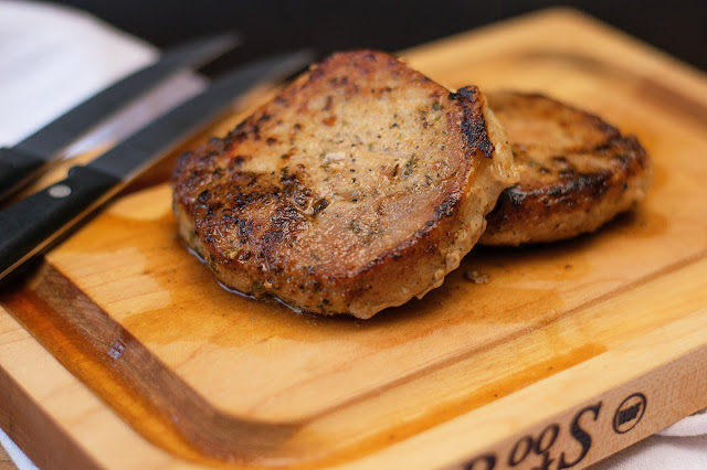 The finished pan seared pork chops on a cutting board.