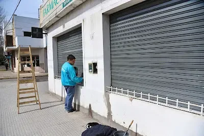Trabajador municipal de La Plata pintando fachada de farmacia como parte del programa Ciudad Limpia