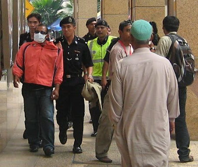 Police bringing an arrestee next to OCBC bank heading towards Masjid Jamek