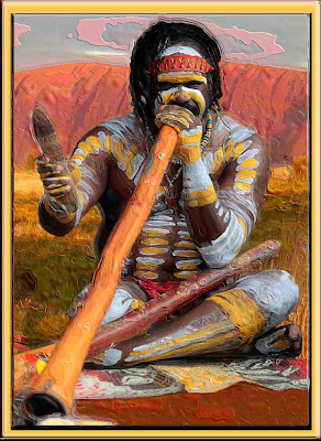 Australian Aborigine playing a dijiridu with Uluru (Ayers Rock) in background.