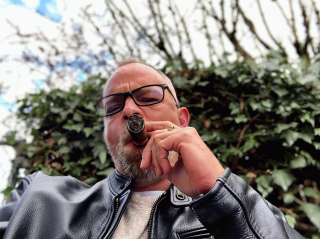 Animation 3/3 Man in his late 40s smoking a cigar wearing a black leather jacket is glasses on
