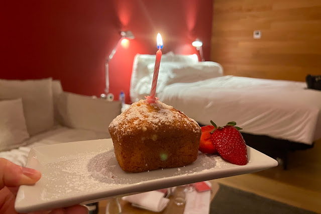 A surprise birthday cake on a plate with bed and sofa in background