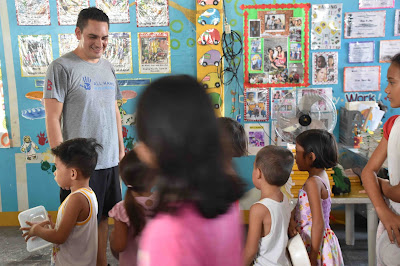 Volunteer man smiling ant children in classroom