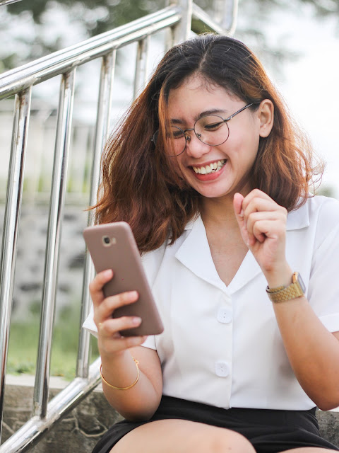 woman smiling at mobile phone in her hand:Photo by Ghen Mar Cuaño on Unsplash