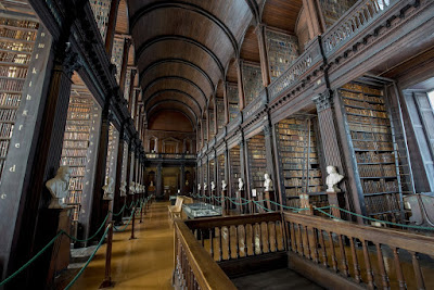 Long library of antique shelving full of books