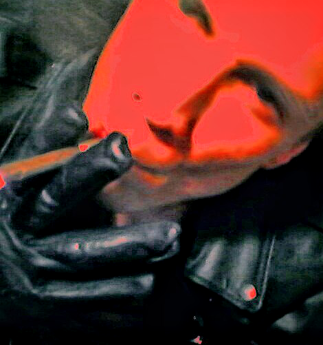 Oregonleatherboy wearing black leather biker jacket and gloves smoking a cigar with a red glow