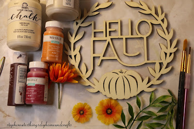 Materials such as paint, wooden hello fall sign and paintbrushes