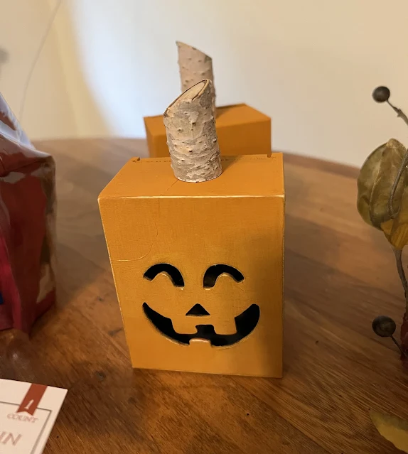 Photo of wooden Jack O' Lanterns with birch branch stems.