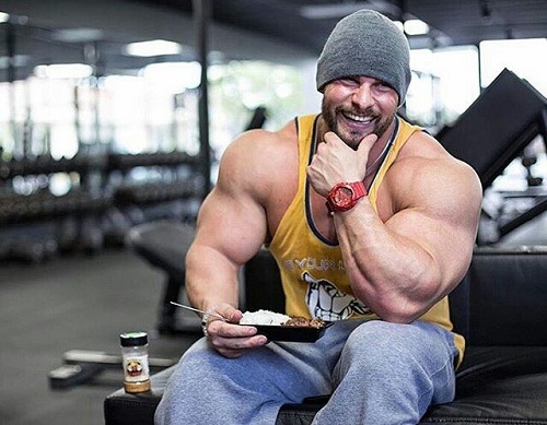 Hombre culturista con un plato de comida en el gimnasio