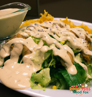 A plate of salad with chicken and creamy lemon dill dressing drizzled on top.