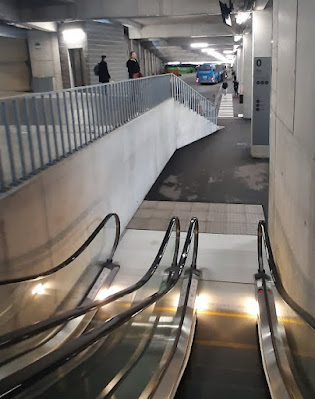 escadas rolantes e escadas normais e algumas pessoas a observar termina rodoviário