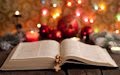 La Sagrada Biblia frente al arbolito de Navidad con esferas y luces de colores