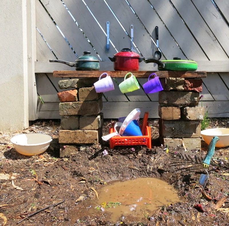 Basic mud kitchen built from bricks and a wooden slab.