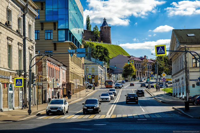 улица с машинами среди зданий на фоне кремля на холме
