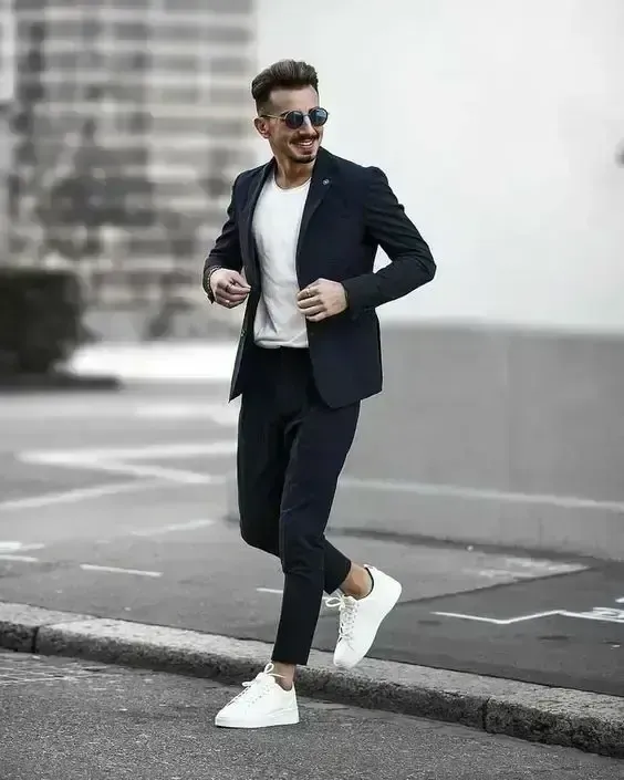 Homem atravessando a rua, usando óculos escuros e blazer azul marinho
