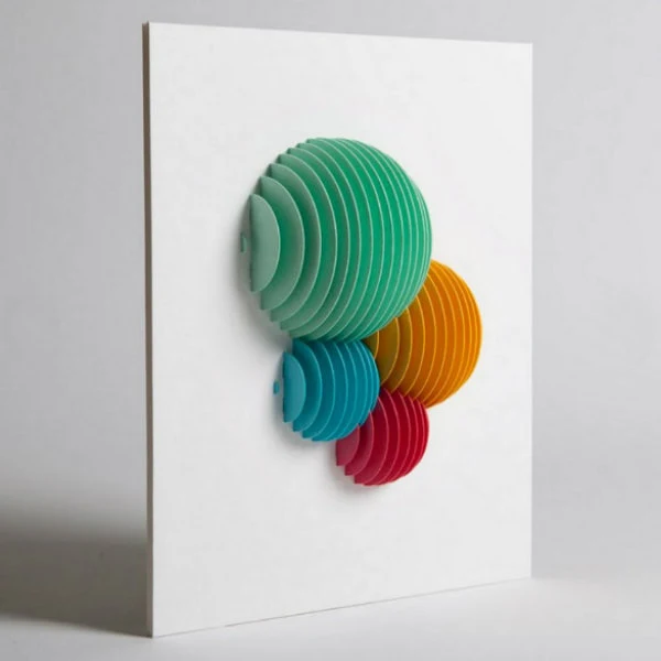 four colors of half circle balls composed of linear, on edge paper pieces mounted on white background