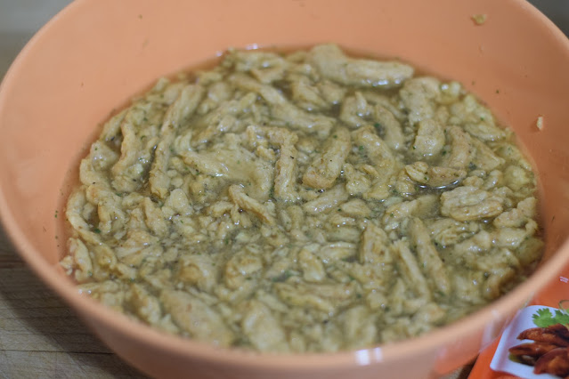 The soy curls reconstituting in warm water, in a bowl, with the vegetable boullion and fajita seasoning.