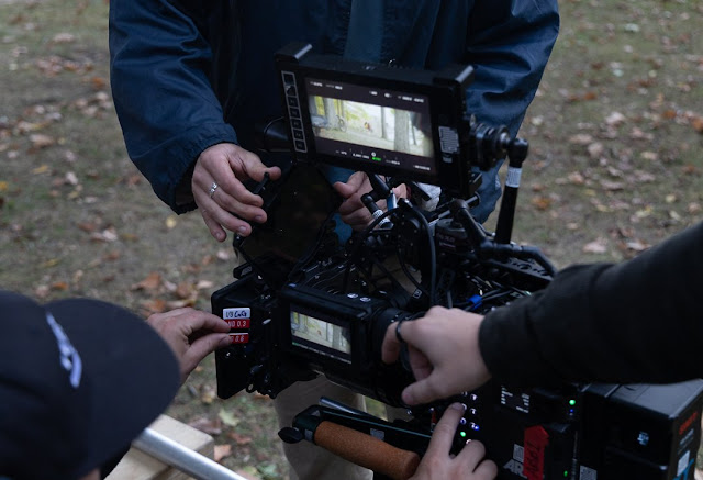 Three people working with film camera equipment on the set of 'Sirens'
