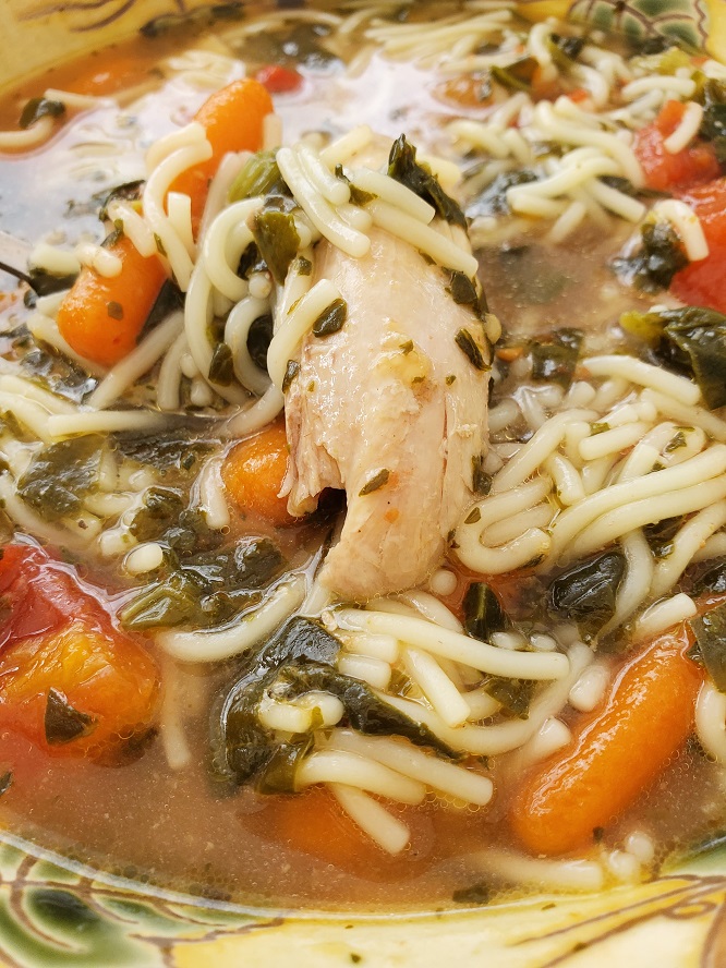 homemade chicken soup with chicken an spinach, carrots, celery in a rich homemade chicken broth