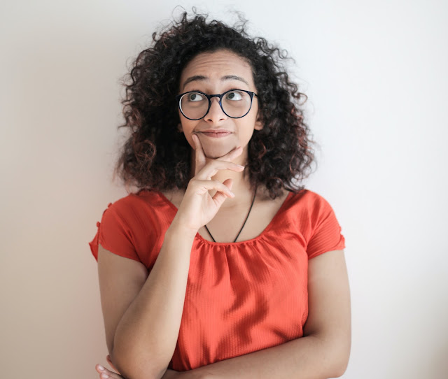 A young lady who wears an orange-coloured blouse thinks about meditation time.