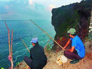 Pemandu pemancing di Gunung Kidul, DI Yogyakarta, Jumidi-kiri, dan pemancing dari Jakarta yang dia dampingi tetap berjaga sekitar pukul 05.00 di Pantai Bekah, Gunung Kidul, Minggu 11.10. Pemandu disebut caddy pemancing tebing ini bisa memperoleh honor Rp 200.000 per malam.