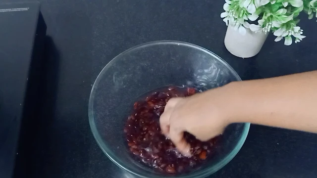 "Dried kidney beans (rajma) being rinsed under running water to remove any dirt or impurities before using them in the recipe."