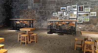 sala de prova de vinhos com várias mesas e bancos de madeira e quadros com fotografias na parede