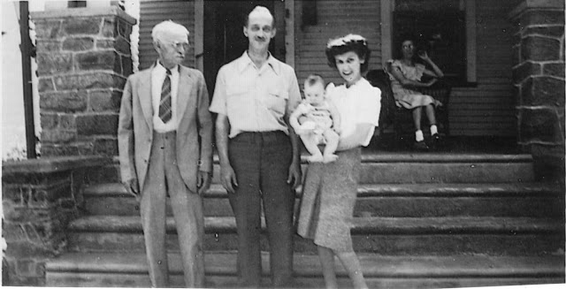 black and white photo circa 1945 showing Lewis Kurtz, son Charles Kurtz (homeowner), Lucy Kurtz holding her baby girl, and Mary Kurtz sitting on the porch