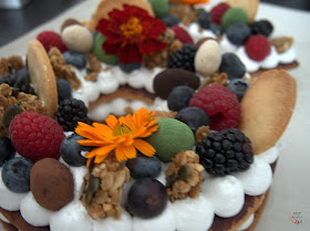 Tarta Adikosh o number cake con base de galleta de masa sucrée, relleno de orange curd y merengue italiano, y decorada con frutos rojos, granola, catanias y flores.