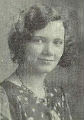 Yearbook photo of a smiling young white woman with bobbed hair, wearing a print dress