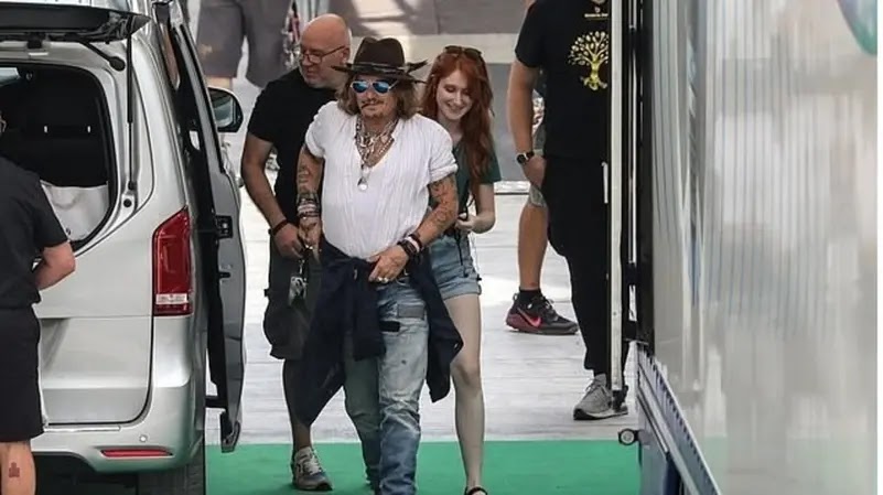 In pictures, Johnny Depp appears "happy" with a mysterious woman in Italy After his victory over his ex-wife Amber Heard in a defamation lawsuit, the news of the Hollywood star, Johnny Depp, continues to top the public's attention, this time with his appearance with a "mysterious" red-haired woman.  The cameras spotted Johnny Depp smiling and looking happy, accompanied by a charming girl, the moment he arrived at the rehearsal at the Arena Santa Giuliana in Italy, in preparation for his participation in the Umbria Jazz Festival, before the start of the concert yesterday, Sunday.  The famous star was also wearing jeans with a white T-shirt, which he coordinated with a brown hat, and hid his eyes with blue glasses.  The unknown woman who accompanied him, walking behind him, was also happy, and wore short jeans with a green T-shirt, brown open shoes, and was carrying a backpack.  Johnny participated in the Umbria Jazz Festival as a special guest at Jeff Beck's concert at the festival, which was held on Sunday.  After the rehearsal, the international star was said to have returned to the Profani Hotel in Perugia, Italy, where the red-haired girl was said to be staying at the same hotel, according to the British newspaper, Daily Mail.  Johnny's latest appearance comes after the release of his new album 18, in which he co-stars with Jeff Beck, as well as after he achieved a new victory in the lawsuit he filed against his ex-wife Amber Heard, specifically after the judiciary rejected her legal team's request for a retrial over allegations that there was an error.