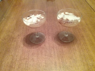 Two campagne coupes, each filled with apple fool (which looks like apple sauce with spices and cream poured over it)