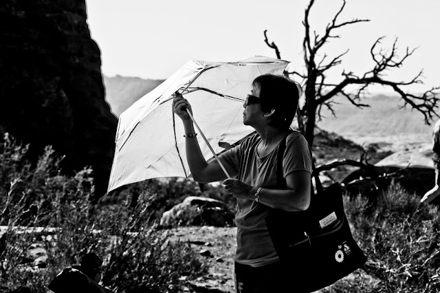 A tourist exploring Arches National Park with a sun umbrella.