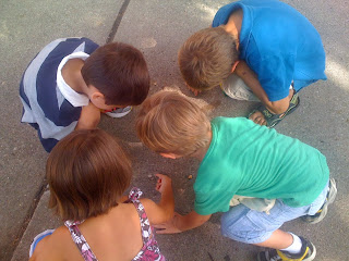 Four kids playing with something on the ground.