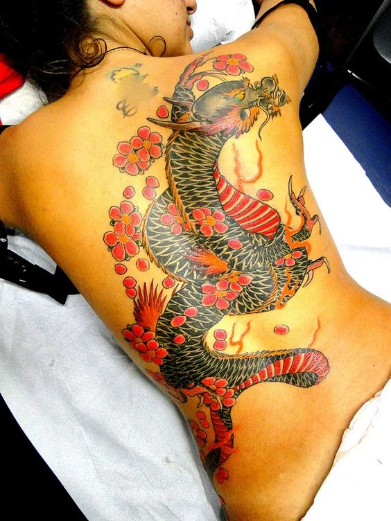 vemos a una mujer posando luce el tatuaje de un dragon