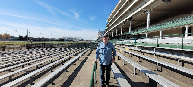 Man standing in stands with track in background