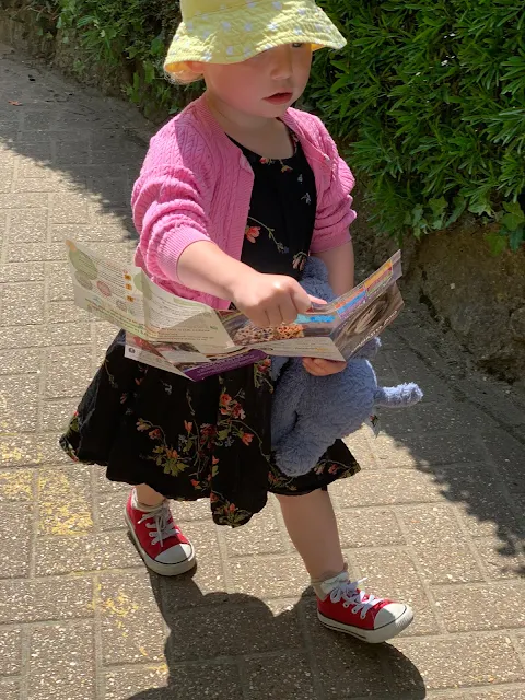 A Toddler dressed ready for a sunny day at the zoo walking with the colchester zoo map