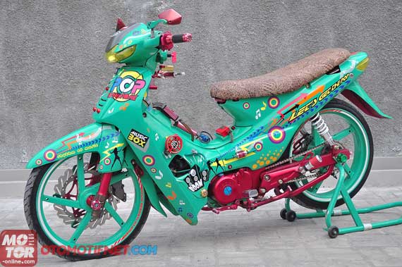 Foto Modifikasi Honda Supra Tema pop art tentu bisa dilihat dari tampilan bodi yang diselubungi cutting stiker bernuansa musik. Misalnya, lewat simbol not balok. Atau, tulisan terbalik ‘Let’s Get The Pop. Begitu juga kaki-kaki.